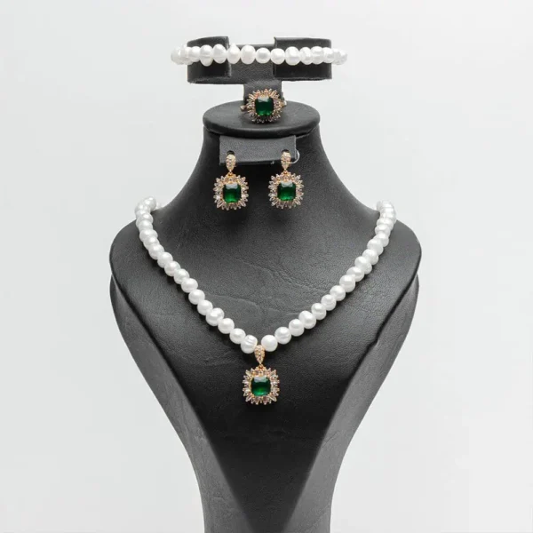 une parure de bijoux de la marque Ascellà Algérie comprenant un collier et un bracelet en perles d'eau douce, des boucles d'oreilles et une bague assorties avec des pierres emerald vert.